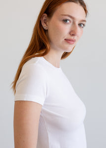 Woman wearing a plain white t-shirt against a light gray background