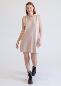 Woman wearing a beige boxy tank dress on a white background