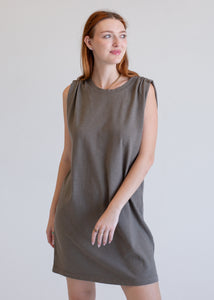 Woman wearing a gray boxy tank dress against a plain background
