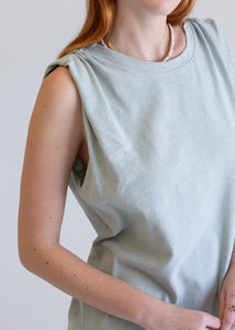 Person wearing a light green boxy tank dress against a plain background