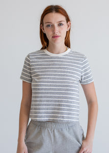 Person wearing a striped shirt and gray pants against a plain background