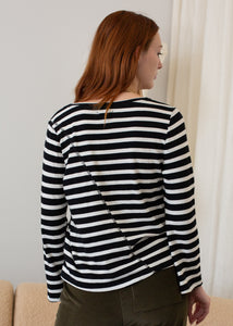 Woman wearing a black and white striped shirt in a neutral setting