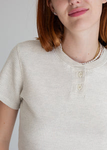 Person wearing a textured beige shirt with a plain background