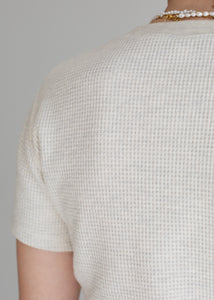 Close-up of a person wearing a textured beige shirt against a gray background