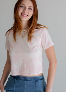 Woman wearing a light pink t-shirt and blue jeans against a plain background