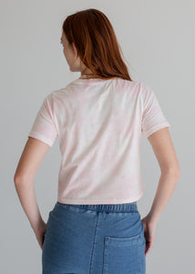 Person wearing a light pink t-shirt and blue jeans on a gray background