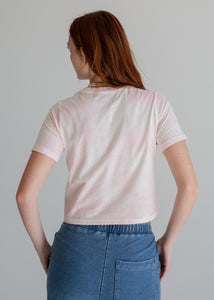 Person wearing a light pink t-shirt and blue jeans on a gray background