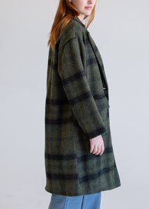 Person wearing a green plaid coat against a plain background