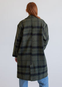 Person wearing a green and navy plaid coat on a white background