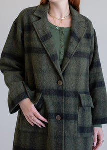 Person wearing a green plaid coat on a plain background