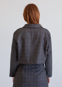Person wearing a plaid jacket and skirt from behind on a plain background