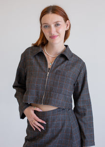 Woman wearing a plaid jacket and skirt set against a plain background