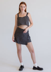 Woman wearing a wool gray plaid tank top with a matching wool gray plaid wrap mini skirt on a white background