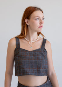 Woman wearing a wool plaid crop top against a plain background