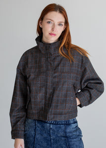 Woman wearing a plaid jacket against a plain background
