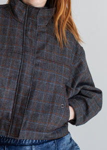 Person wearing a plaid jacket with a neutral background