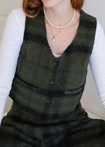 Person wearing a green vest over a white shirt with visible jewelry.