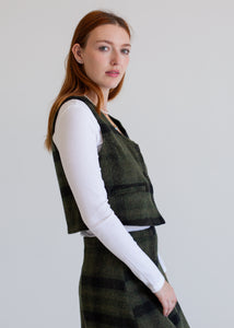 Woman wearing a green plaid skirt with a matching vest against a white background